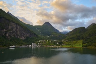 Geiranger with fjord landscape with mountains embedded in nature, covered by dramatic clouds,