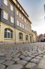 City street with traditional buildings, cobblestones and cloudy sky, Harz Mountains, Germany,