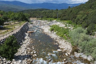 Landschaft mit einem gebirgigen Fluss, der durch eine grüne und steinige Landschaft fließt, umgeben