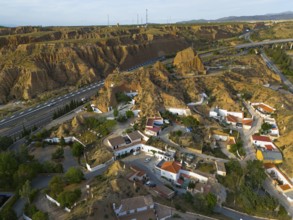 Aerial view of a housing estate in a rocky, hilly environment with cave houses and streets, aerial