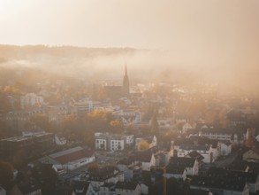 Town in the morning mist with prominent church spire and autumn landscape, Nagold, Black Forest,