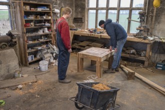 Father looks at his son's finished table in the workshop, Mecklenburg-Vorpommern, Germany, Europe