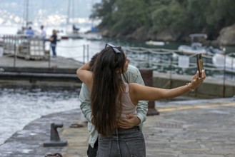 Couple taking a selfie of themselves in the harbour of Potofino, Italy, Europe