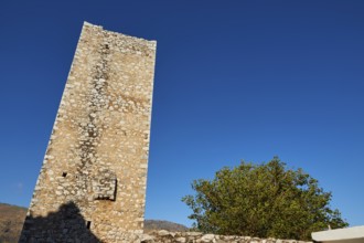 Standing old tower made of pebbles under a bright blue sky, Flomochori, residential towers village,