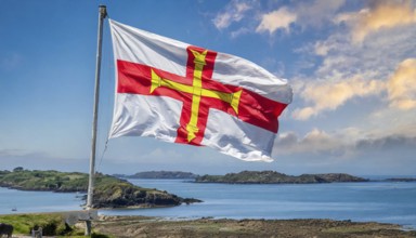 The flag of the Isle of Guernsey, Great Britain, flutters in the wind