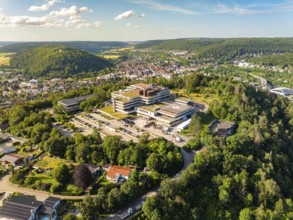 Large building in the middle of a lush green landscape and city, taken from the air under a summer