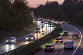 Evening scene on a motorway with heavy traffic, illuminated by headlights under a twilight sky,