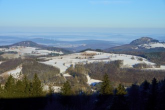 Snow-covered hilly landscape under a blue sky with trees in the foreground, Milseburg,