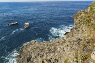 Rocky cliff and fishing boats moored in bay, Ligurian Sea, Manarola village in late summer, Cinque