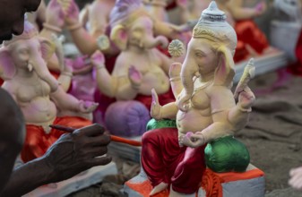 An artisan decorates an idol of the elephant-headed Hindu deity Ganesha at a workshop ahead of the