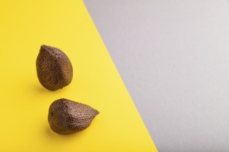 Salak or snake fruit on gray and yellow pastel background. Side view, copy space. Tropical, healthy