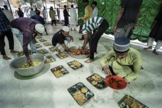 Volunteers distribute and arrange rows of 'iftar' meal for devotees to break their fast, during the