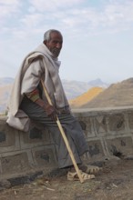 In the highlands between Mekele and Lalibela, elderly man with stick waiting by the road, Ethiopia,