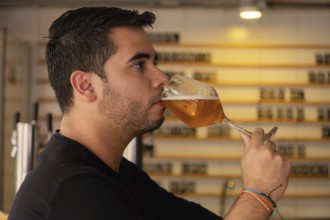 A young man enjoys a glass of beer in a cozy pub or restaurant. The warm and cozy atmosphere