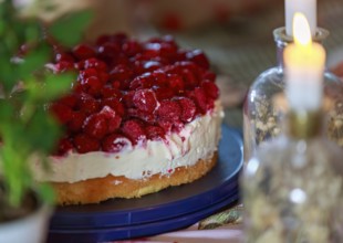 A decorative raspberry cake with cream and candlelight that creates a romantic atmosphere