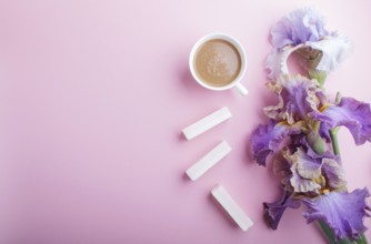 Purple iris flowers and a cup of coffee on pastel pink background. Morninig, spring, fashion