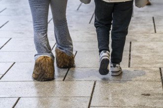 2 woman walking in the rain, one woman wears boots with long fur, wet, dirty, water splashes on her