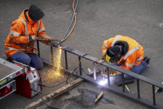 Locksmith at work, cutting and welding, on a workpiece in an industrial plant, a metal ladder is