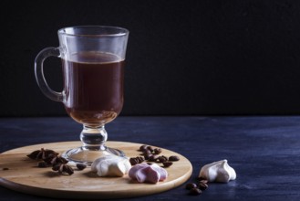 Glass cup of coffee with meringues on a wooden board on a black background. close up, copy space