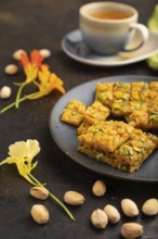 Traditional iranian dessert sohan with cup of green tea on a black concrete background and green