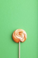 Single lollipop candy on green pastel background. copy space, top view, flat lay