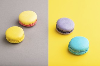 Yellow, purple and blue macaroons on trendy gray and yellow background. side view, copy space,