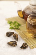 Red tea with herbs in glass on gray concrete background and linen textile. Healthy drink concept.