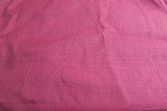 Fragment of smooth cotton purple tissue. Side view, natural textile background and texture