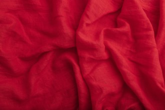 Fragment of red linen tissue. Top view, natural textile background and texture. wave concept,