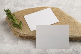 White paper business card, mockup with natural stone and boxwood branch on gray concrete background