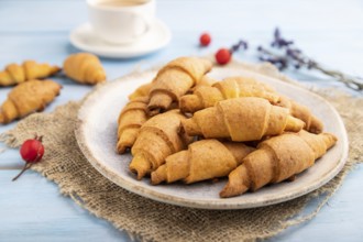 Homemade bagel roll with cup of coffee on a blue wooden background and linen textile. side view,