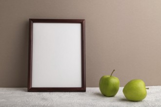 Brown wooden frame mockup with green apple on beige paper background. Blank, vertical orientation,