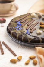 Homemade chocolate brownie cake with caramel cream and almonds with cup of coffee on a white