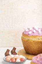 Homemade glazed and decorated easter pies with chocolate eggs and rabbits on a white concrete