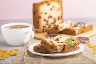 Homemade cake with raisins, dried persimmon and a cup of hot chocolate on a gray concrete