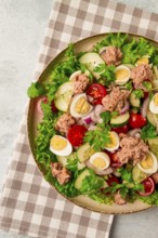 Tuna salad, vegetable salad with quail eggs, lettuce, red onion and cucumbers, on a light gray