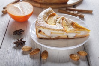 A slice of sweet persimmon pie on white wooden background. close up