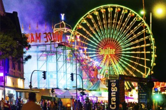 Cranger Kirmes with colourfully illuminated fairground rides and the Ferris wheel at night, Herne,