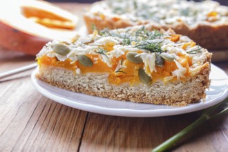 A piece of sweet pumpkin pie with cheese and dill on brown wooden background. close up