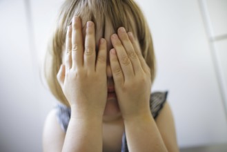 Symbolic photo on the subject of fear in children (posed scene) . A little girl holds her hands in