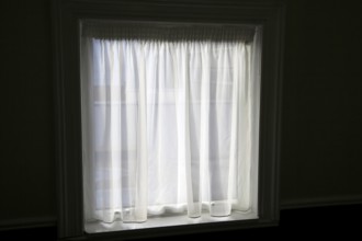 Net curtain in window of dark room letting in light