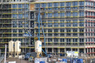 Large construction site, scaffolded shell of an office building complex, air hoses for construction