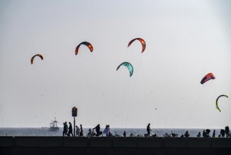 Kitesurfer off the coast of Scheveningen, walkers on the harbour pier, The Hague, Netherlands