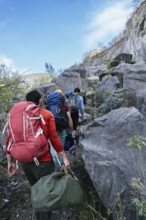 Rear view of a group of hikers hiking picturesque mountain trails in a row, immersed in the beauty