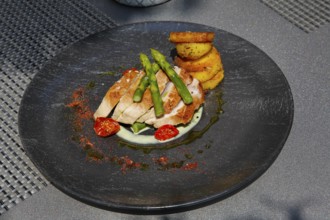 Tuna steak with green asparagus, fried potatoes served on a plate, main course, fish dish, Hotel