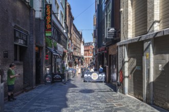 Narrow alley with shops and pubs, lively with passers-by, Liverpool