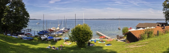 Panoramic view of a lake with sailing boats, surrounded by green meadow and trees on a sunny day,