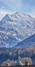 Snow-covered mountain with a church in the foreground under a clear blue sky, Bad Feilnbach