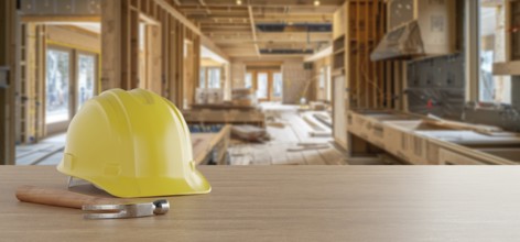 Yellow hard hat and hammer on a wood background with home renovation in construction site in the