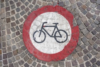 Pictogram for cycling prohibited painted on a cobblestone pavement in the old town centre of